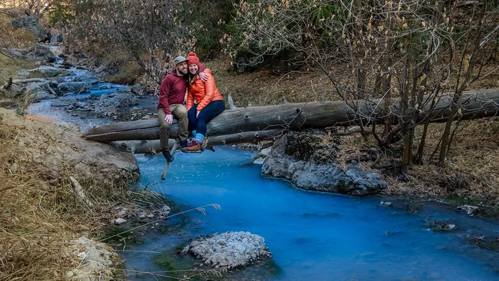 Kent and Chelle sitting on a log over a creek